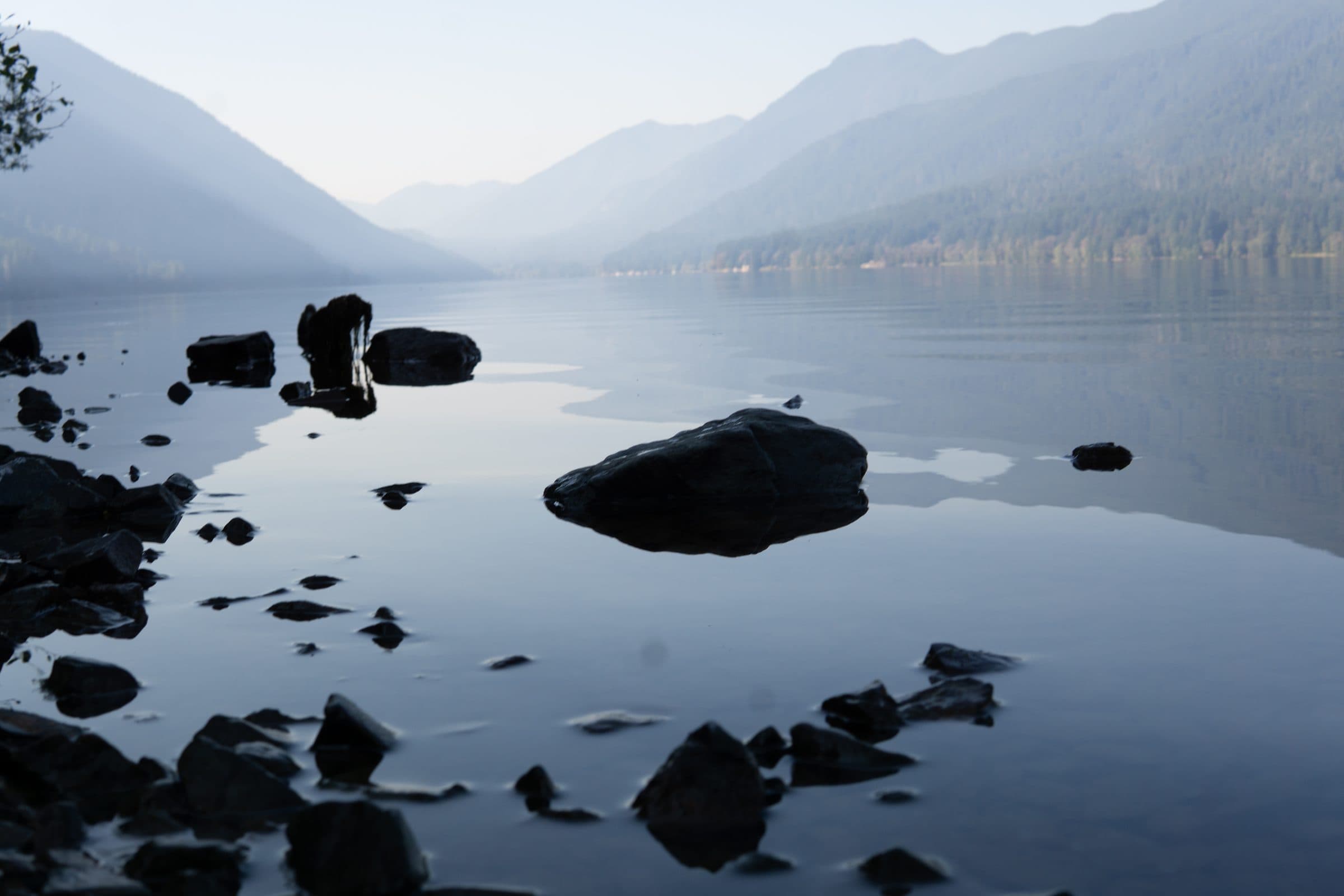 A still, misty lake between mountains